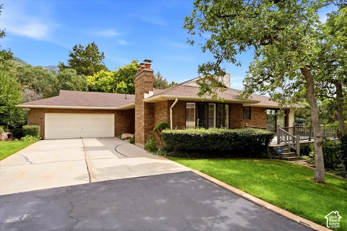 Brick exterior, attached garage, multi-level composite deck, mature trees, and established landscaping