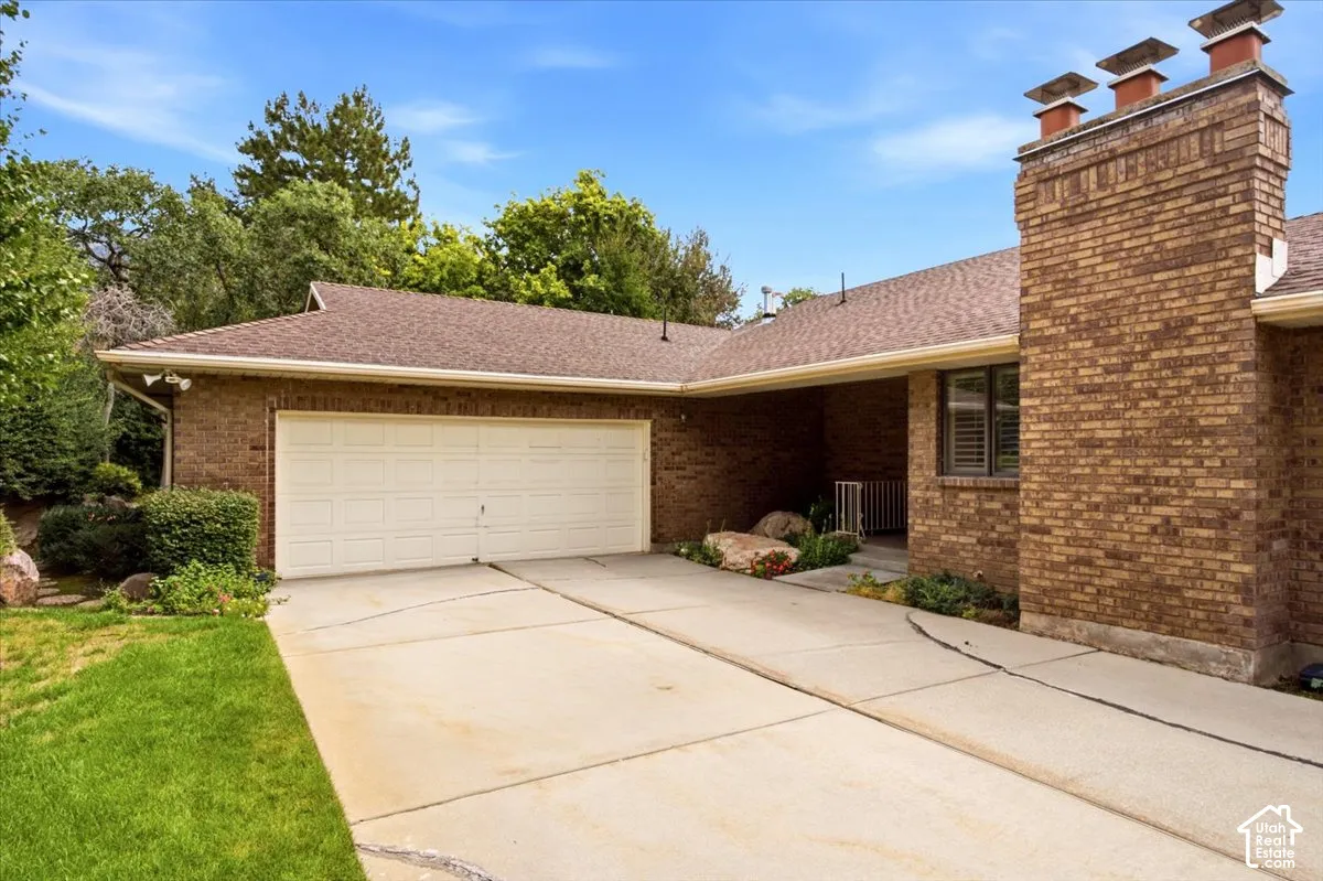Brick exterior with a multi-level roofline, attached garage, and a prominent brick chimney