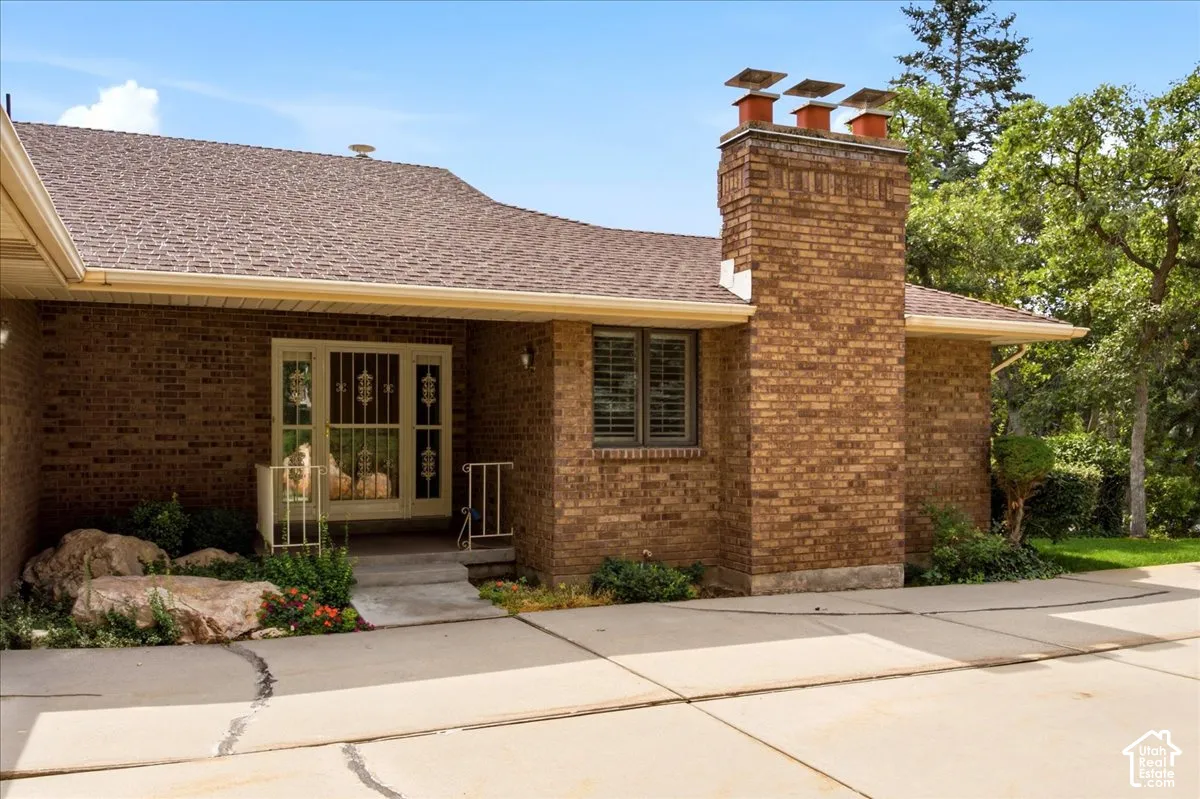 Brick exterior featuring a multi-flue chimney, a covered entryway, and a full-light entry door with decorative security bars