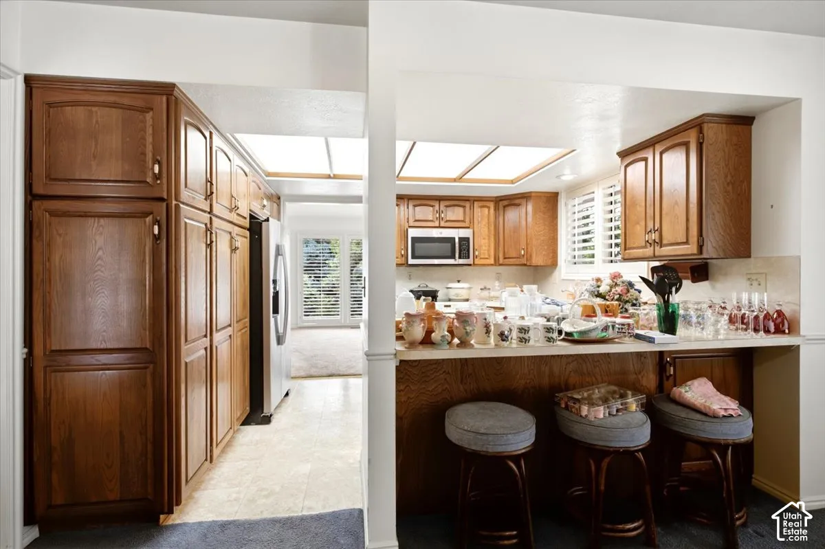 Kitchen featuring wood cabinetry, a breakfast bar, recessed lighting, and a skylight