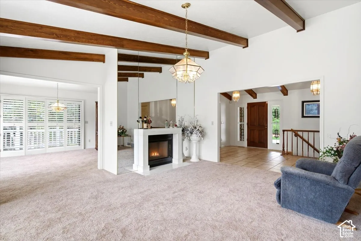 Vaulted ceilings with exposed wood beams, a prominent fireplace with a white mantel, and extensive plantation shutters