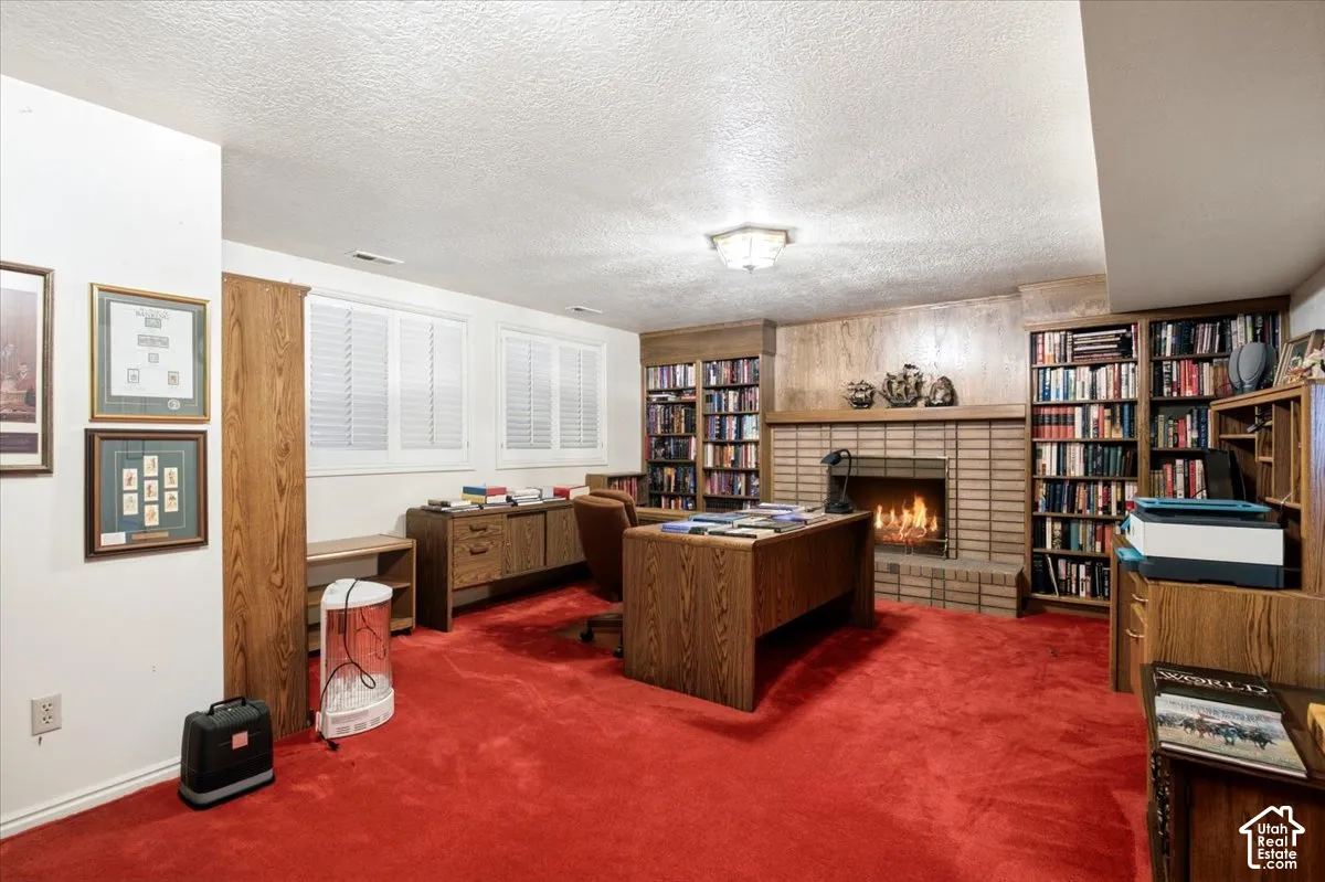 Brick-surround fireplace with hearth, recessed built-in shelving, white plantation shutters, and overhead lighting