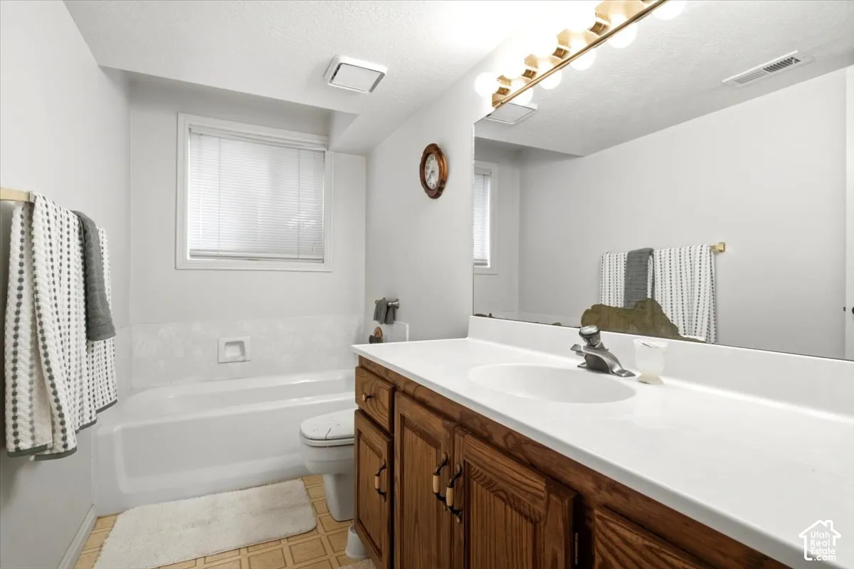 Single vanity with wood-finish cabinetry, white countertop, and integrated sink
