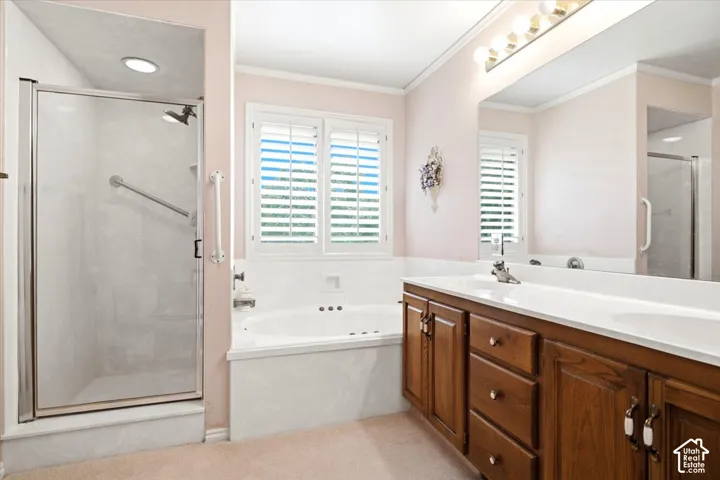Dual vanity with integrated sinks, wood-finish cabinetry, built-in soaking tub, glass-enclosed shower, and window with plantation shutters