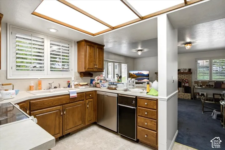 Kitchen featuring wood cabinetry, white plantation shutters, stainless steel dishwasher, and a built-in electric range
