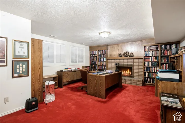 Brick-surround fireplace with hearth, recessed built-in shelving, white plantation shutters, and overhead lighting