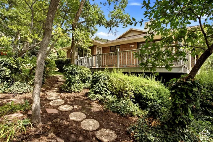 Lush landscaping with mature trees, a stone pathway, and an exterior brick finish