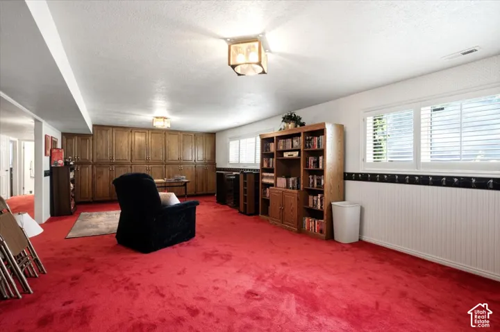 Expansive room featuring red carpeting, extensive built-in wooden cabinetry, recessed lighting, and windows with plantation shutters