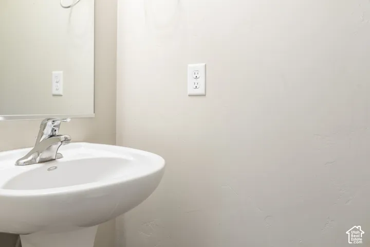 Pedestal sink with chrome-finish faucet and wall mirror