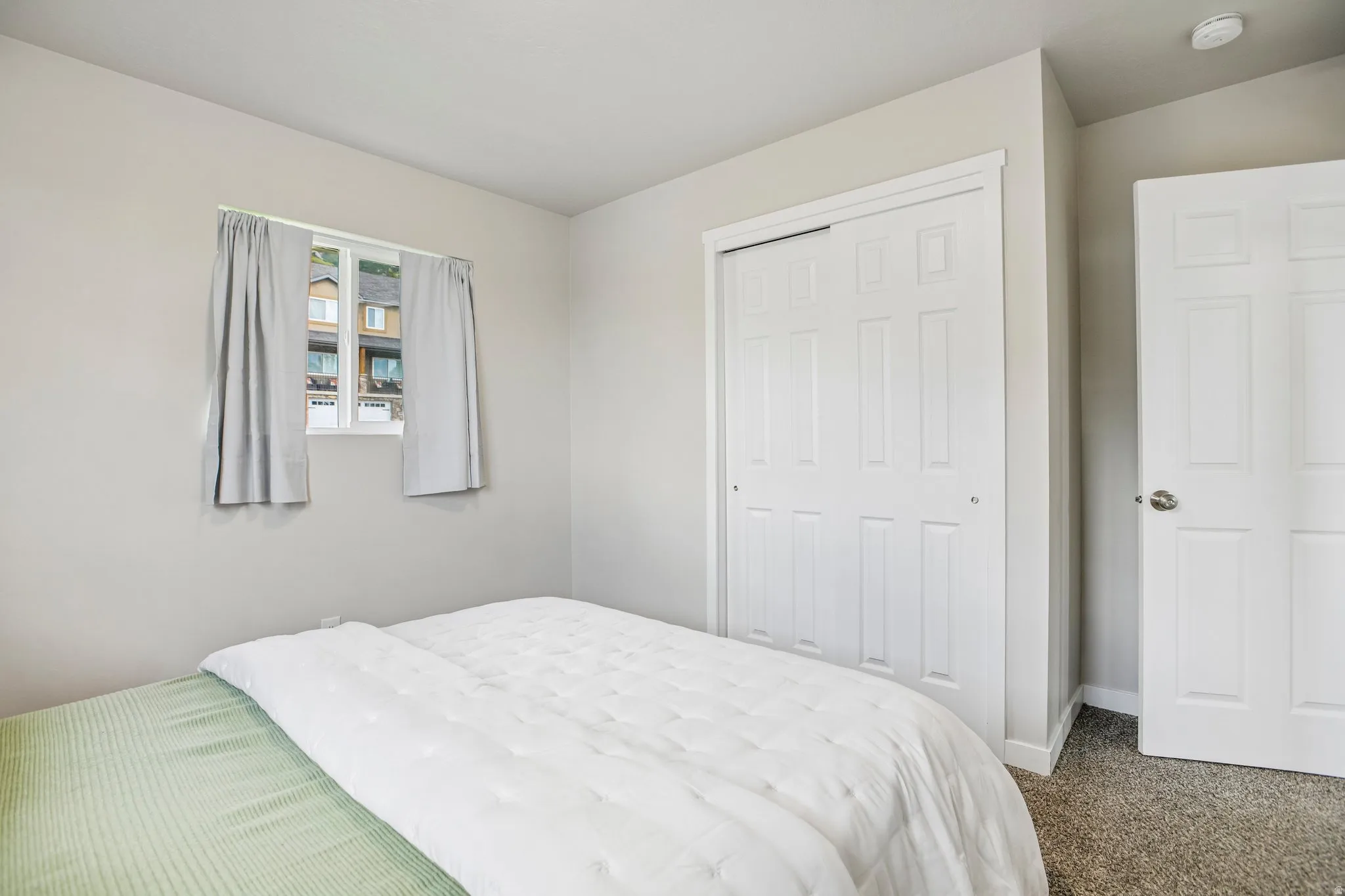 Light-colored walls, white trim, carpeted flooring, and a window with white casing
