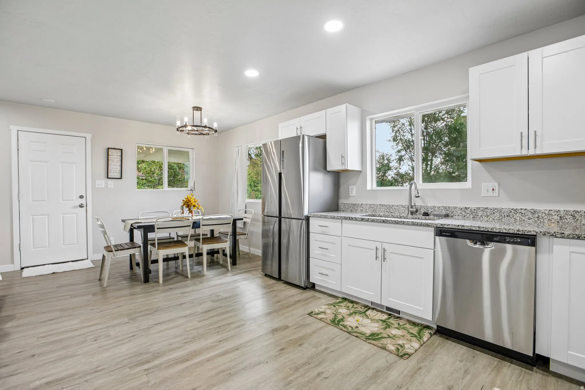 Kitchen featuring wood-finish flooring, white cabinetry, stainless steel appliances, speckled countertops, and recessed lighting