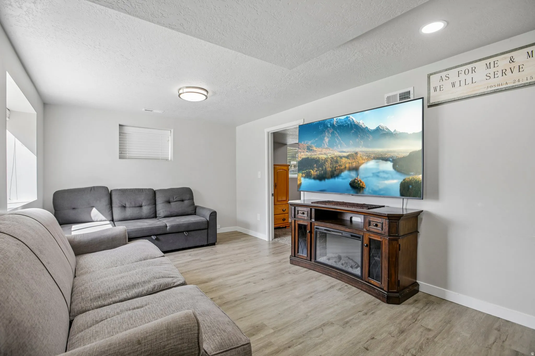 Wood-finish flooring, recessed lighting, and a built-in electric fireplace media console