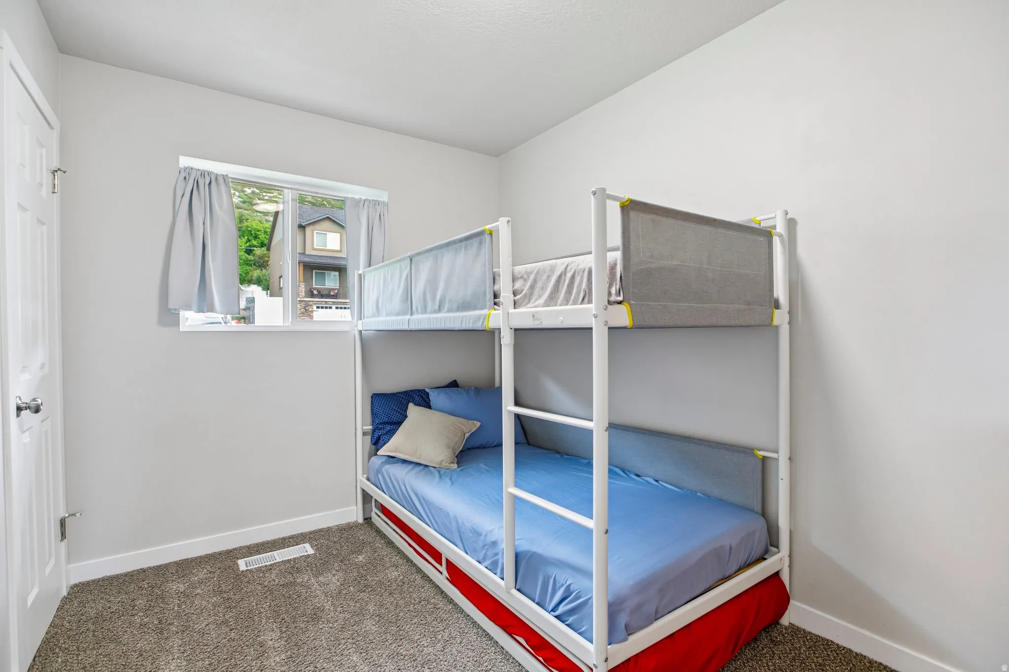 Neutral wall color, window with a white frame, and plush carpet flooring