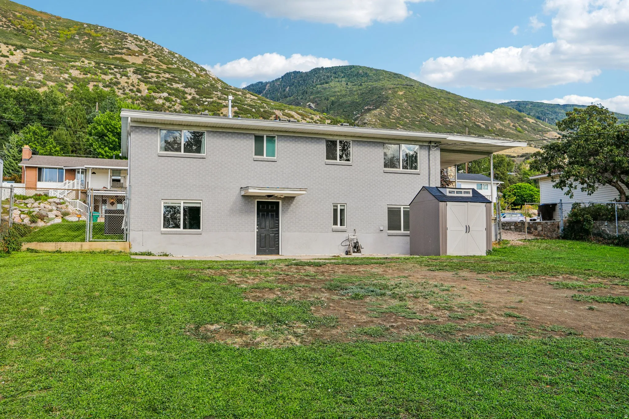 Two-story exterior with a covered patio and a separate storage shed