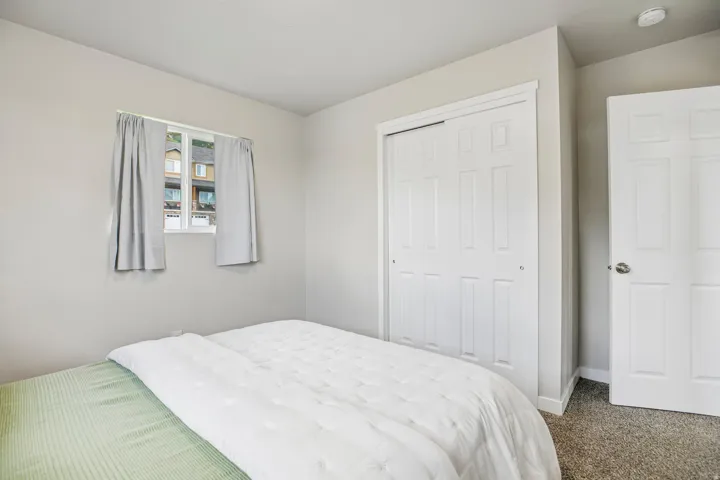 Light-colored walls, white trim, carpeted flooring, and a window with white casing
