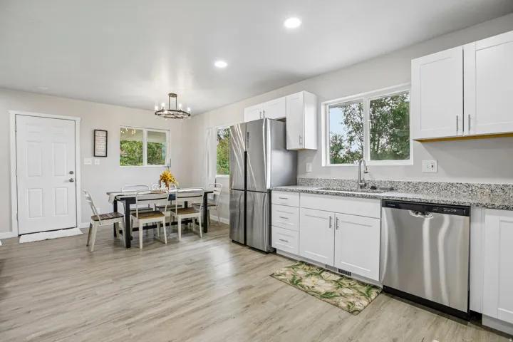 Kitchen featuring wood-finish flooring, white cabinetry, stainless steel appliances, speckled countertops, and recessed lighting