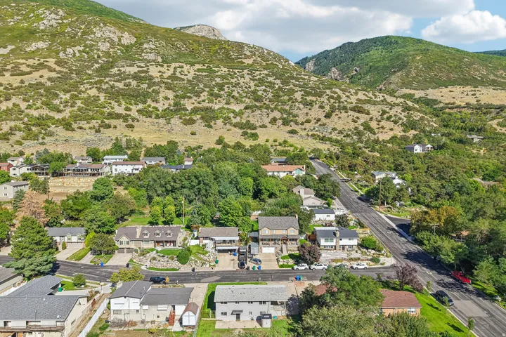Residential properties nestled within a mountainous landscape featuring mature trees and paved roadways