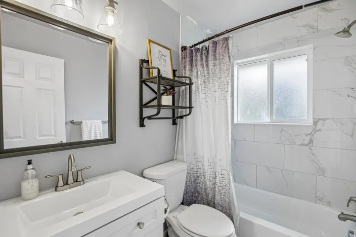 Bathroom featuring a single vanity, framed mirror, light gray wall paint, and white subway tile bath surround