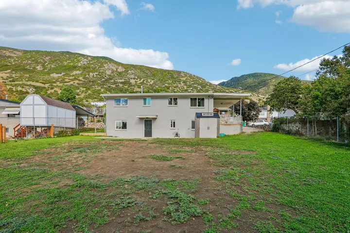 Expansive backyard with a two-story residence featuring a covered patio, exterior storage shed, and a detached outbuilding