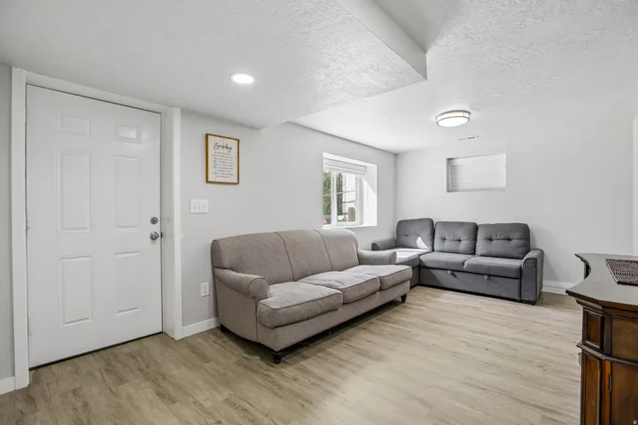 Recessed ceiling lighting, wood-finish flooring, white trim, and a window with blinds