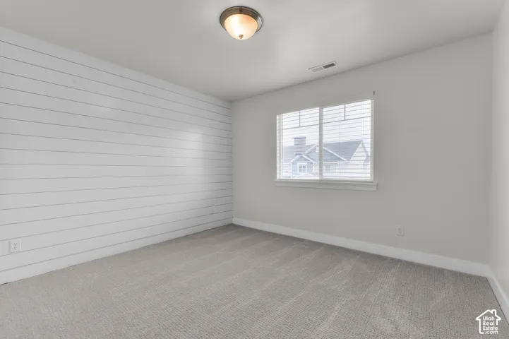 Shaker-style wall paneling, flush mount ceiling light fixture, window with blinds, and neutral carpet flooring