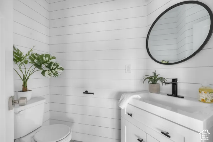 White shiplap walls complement a modern vanity with integrated sink and black hardware