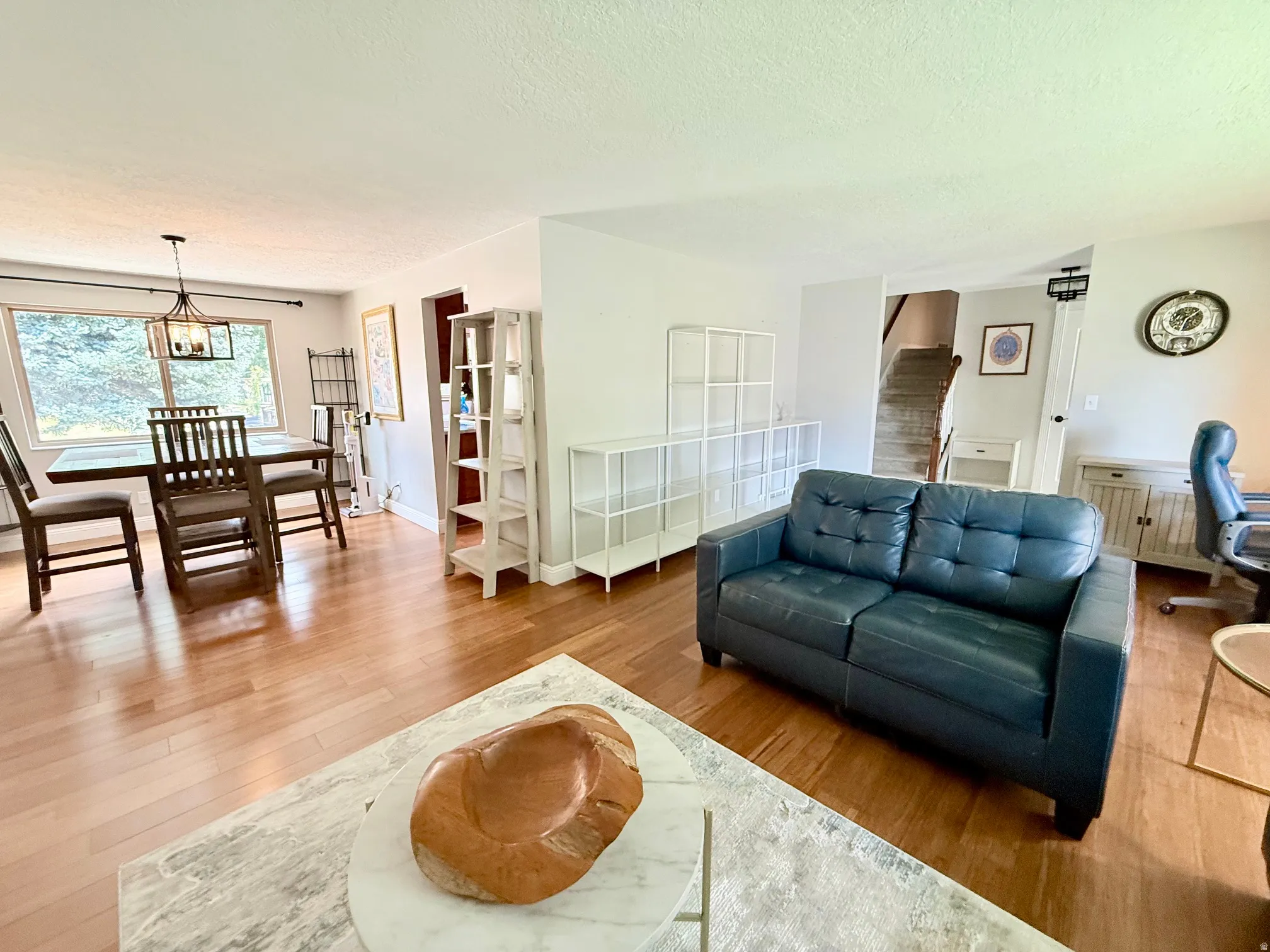 Hardwood-style flooring throughout, with a dining area featuring a modern chandelier and large windows