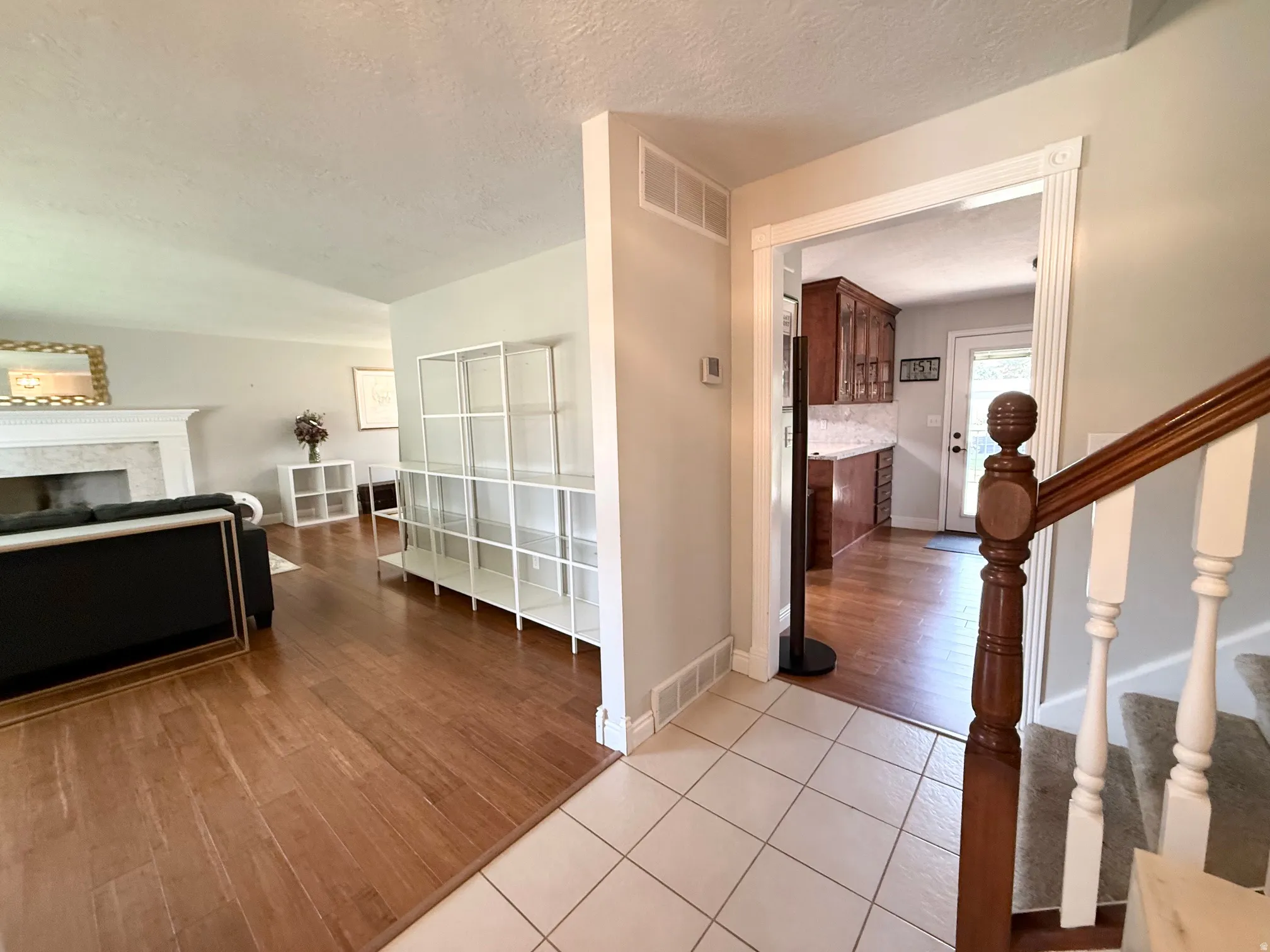 Foyer with ceramic tile flooring, wood-finish flooring, and a staircase with wood banister and white risers
