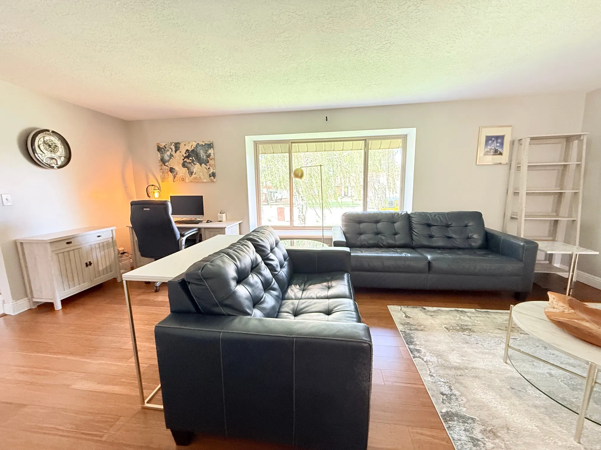 Warm wood-finish flooring, large window, white trim, and light wall color