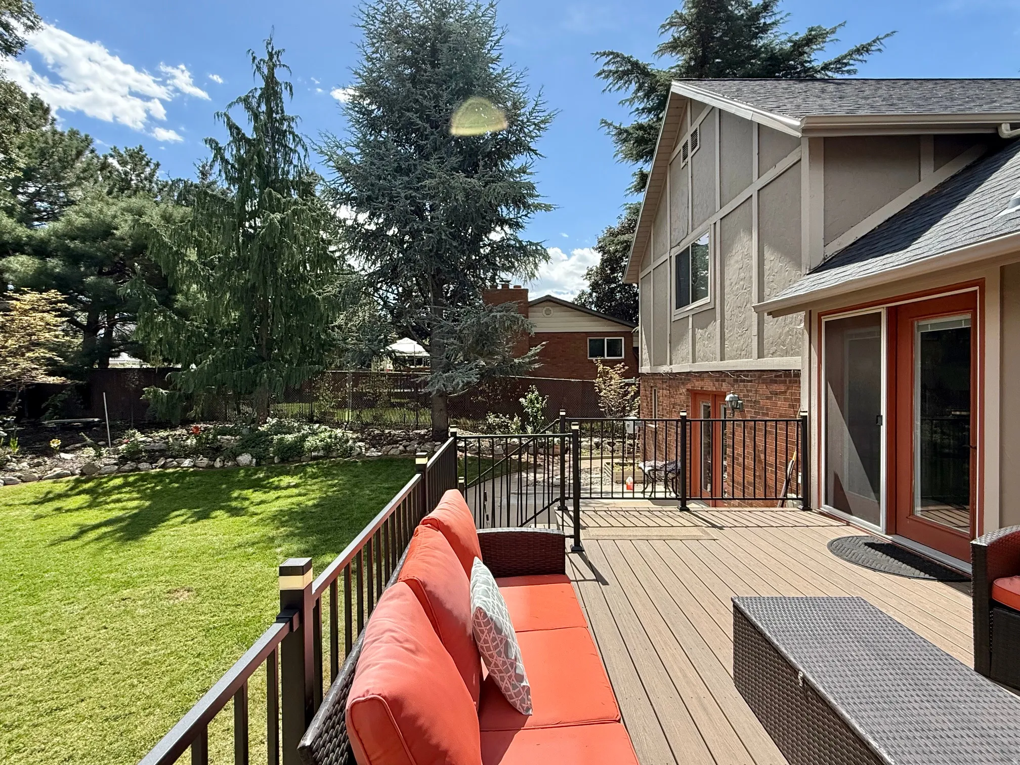 Expansive composite deck with black metal railings, offering direct access to a large grass lawn