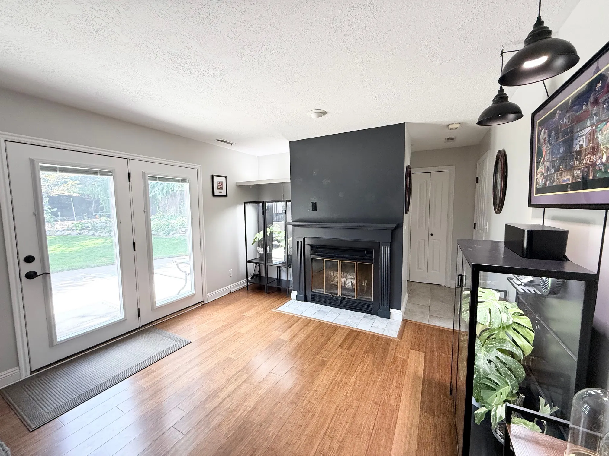 Wood-finish flooring throughout, paired with a fireplace featuring a black mantel and white tile hearth