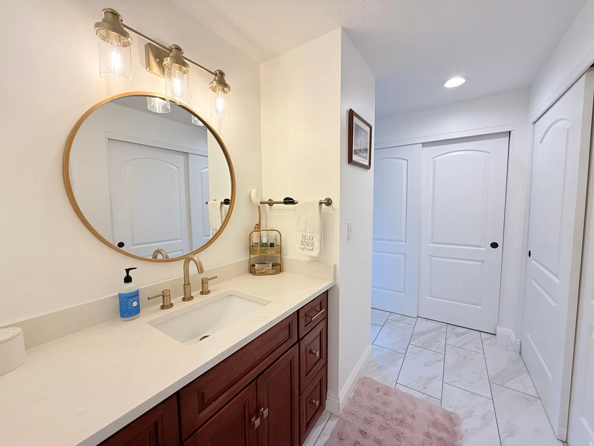 Bathroom featuring a vanity with a white countertop, an undermount sink, and a gold-toned faucet