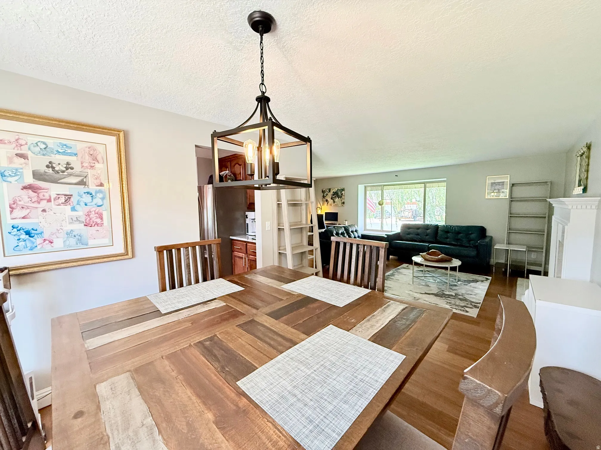 Wood-finish flooring throughout, with a decorative open-cage chandelier, and a built-in fireplace mantel
