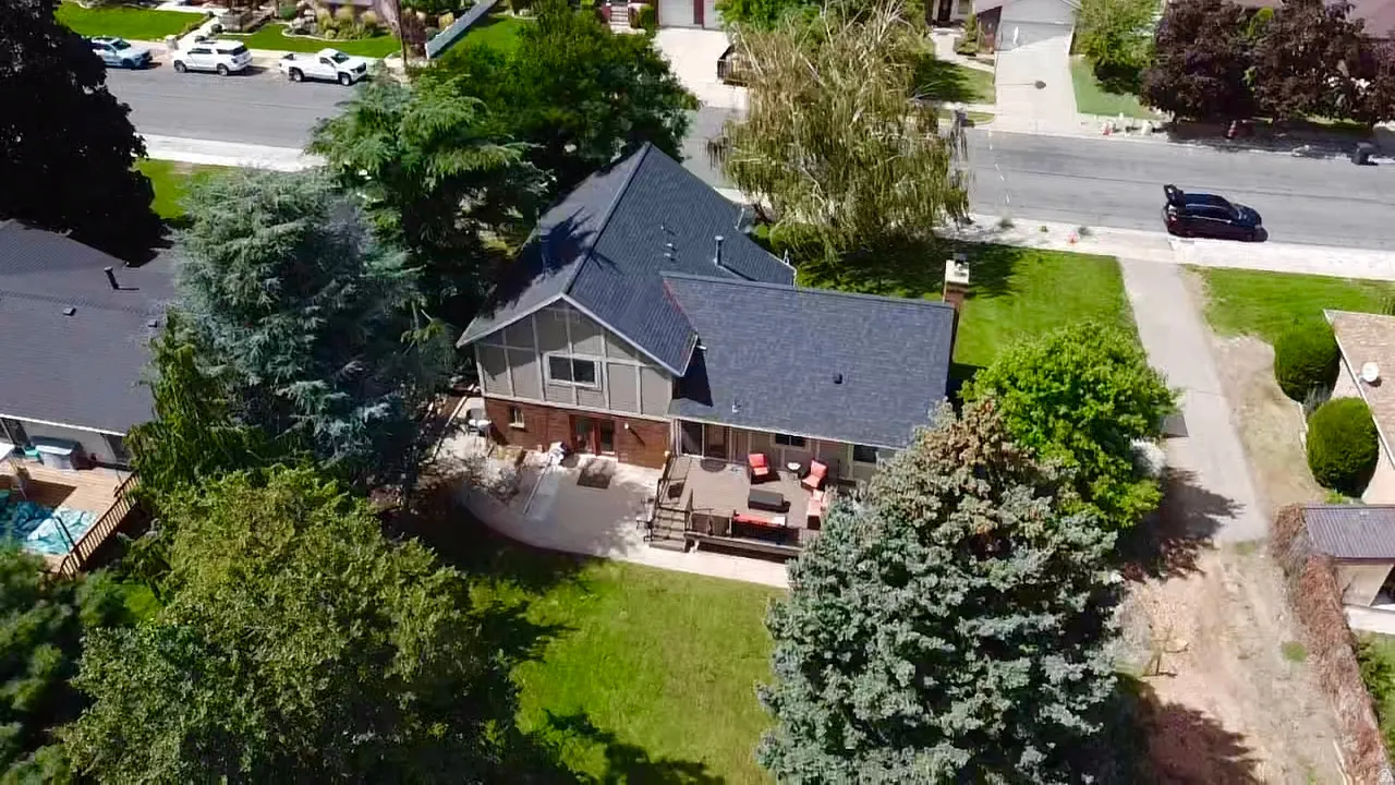 Expansive backyard featuring a manicured lawn, mature trees, and a multi-level deck