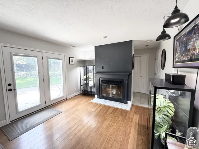 Wood-finish flooring throughout, paired with a fireplace featuring a black mantel and white tile hearth