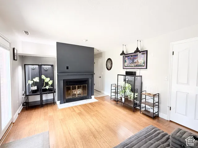 Hardwood-finish flooring throughout, a gas fireplace with a dark mantel, a glass sliding door, and white panel doors