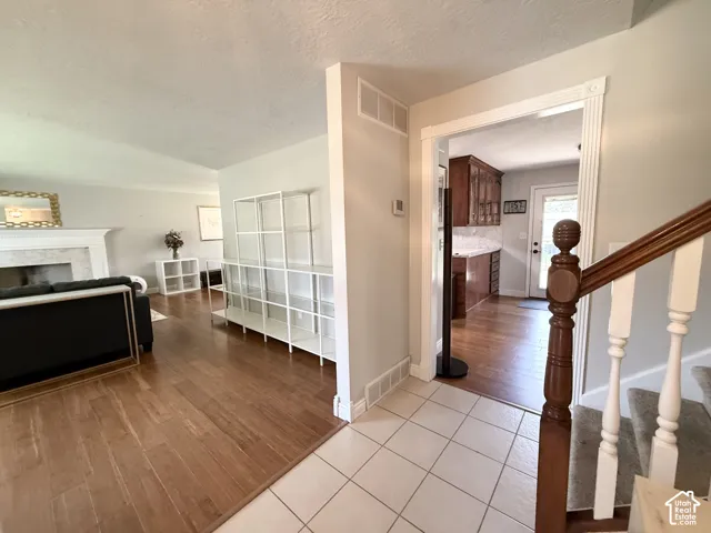 Foyer with ceramic tile flooring, wood-finish flooring, and a staircase with wood banister and white risers