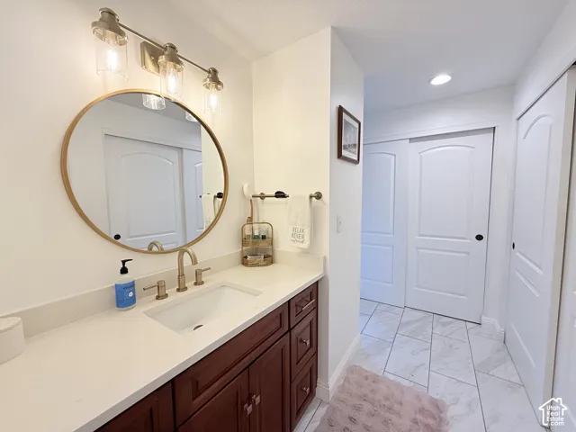 Bathroom featuring a vanity with a white countertop, an undermount sink, and a gold-toned faucet