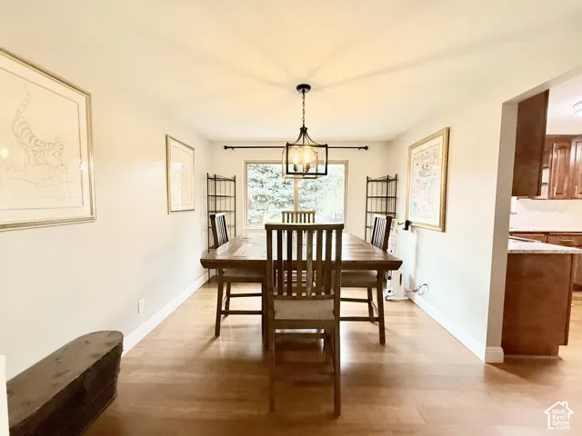 Dining area featuring wood-finish flooring, a contemporary geometric pendant light, and a large window