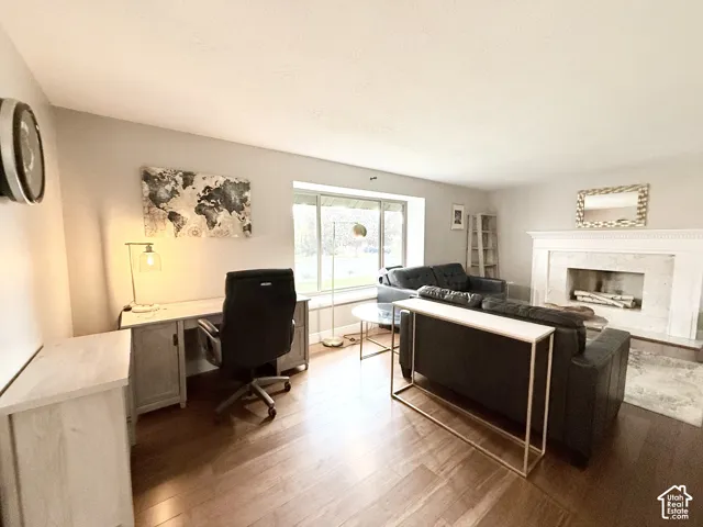 Living area featuring wood-finish flooring, a fireplace with a white mantel, and a bay window