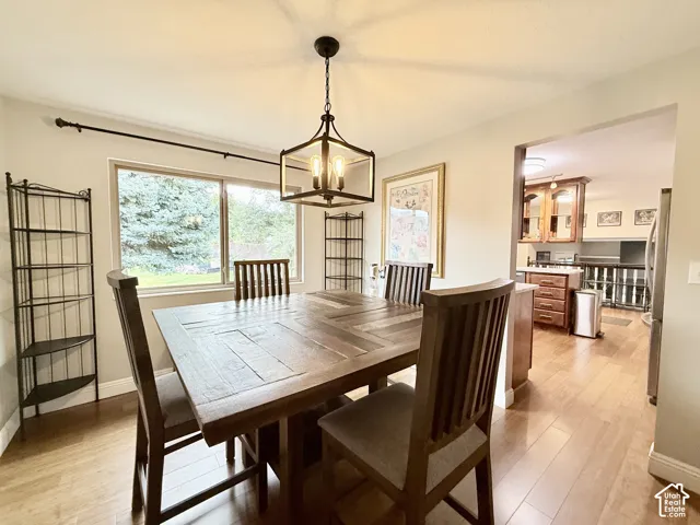 Dining area featuring wood-finish flooring, a matte black metal cage-style chandelier, and a large horizontal window