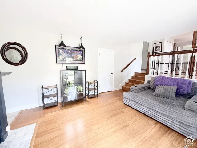 Hardwood flooring, painted white walls, wood staircase with white balusters, white paneled door, and built-in shelving