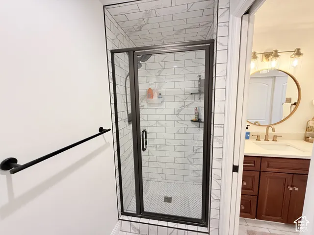 Glass-enclosed shower with white subway tile surround, herringbone pattern shower floor, and matte black fixtures