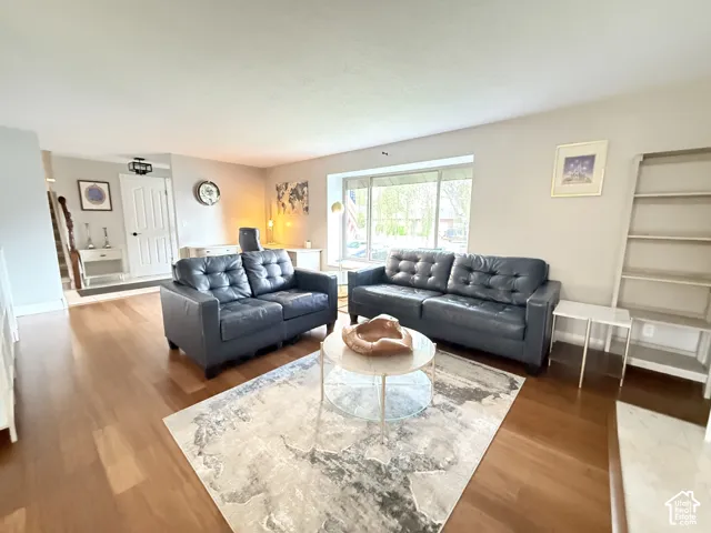 Living area featuring wood-finish flooring, a large bay window, and a built-in shelving unit