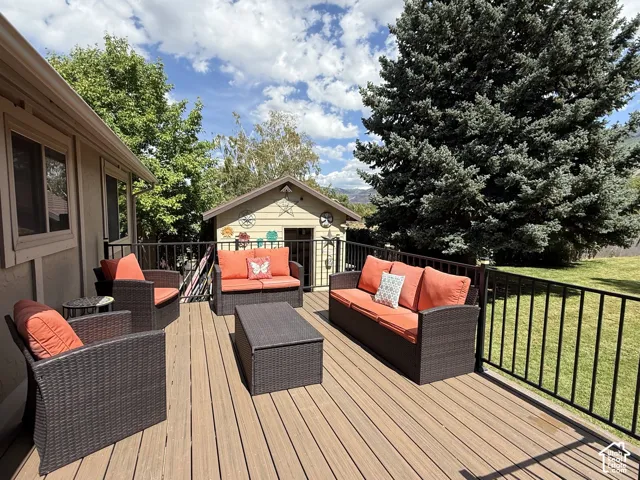 Spacious outdoor deck with composite decking and black metal railings, featuring a detached shed and expansive green lawn