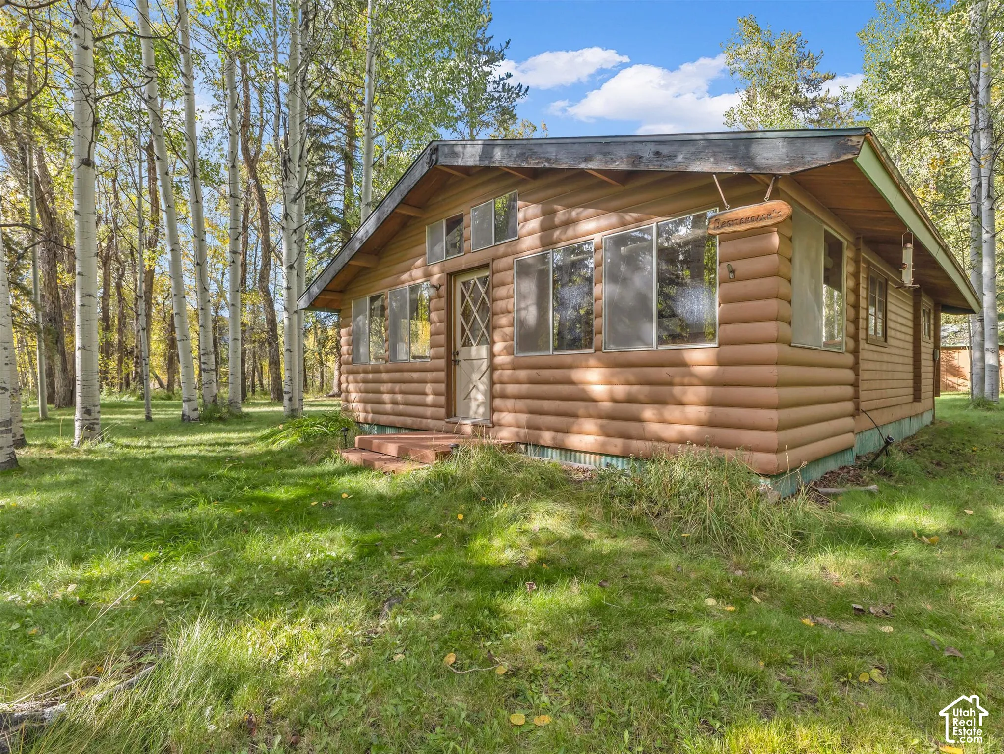 Log cabin exterior with a pitched roof, multiple windows, and a set of wooden steps