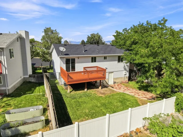 Rear exterior with siding, a dark roof, and a wood deck