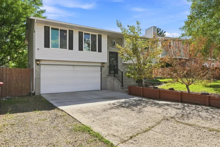 Split-level residence featuring a two-car garage, concrete driveway, and an elevated front entrance with railings