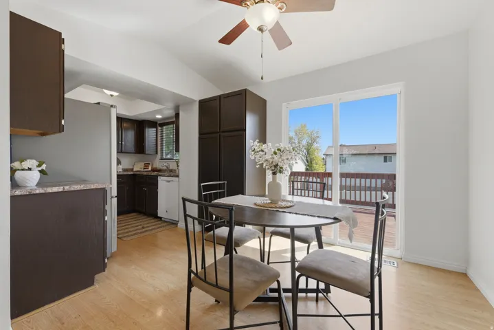 Vaulted ceiling with a ceiling fan, light wood-finish flooring, sliding glass door, and an attached deck