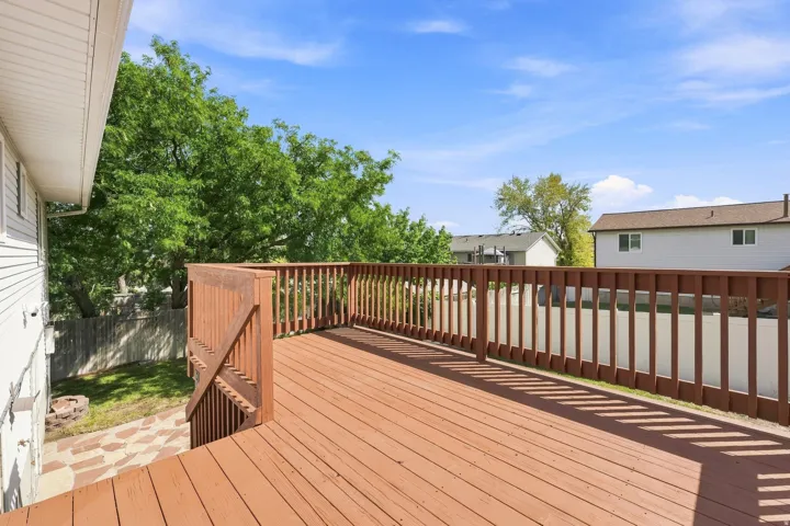 Expansive wood-finish deck with full railing and steps to the yard